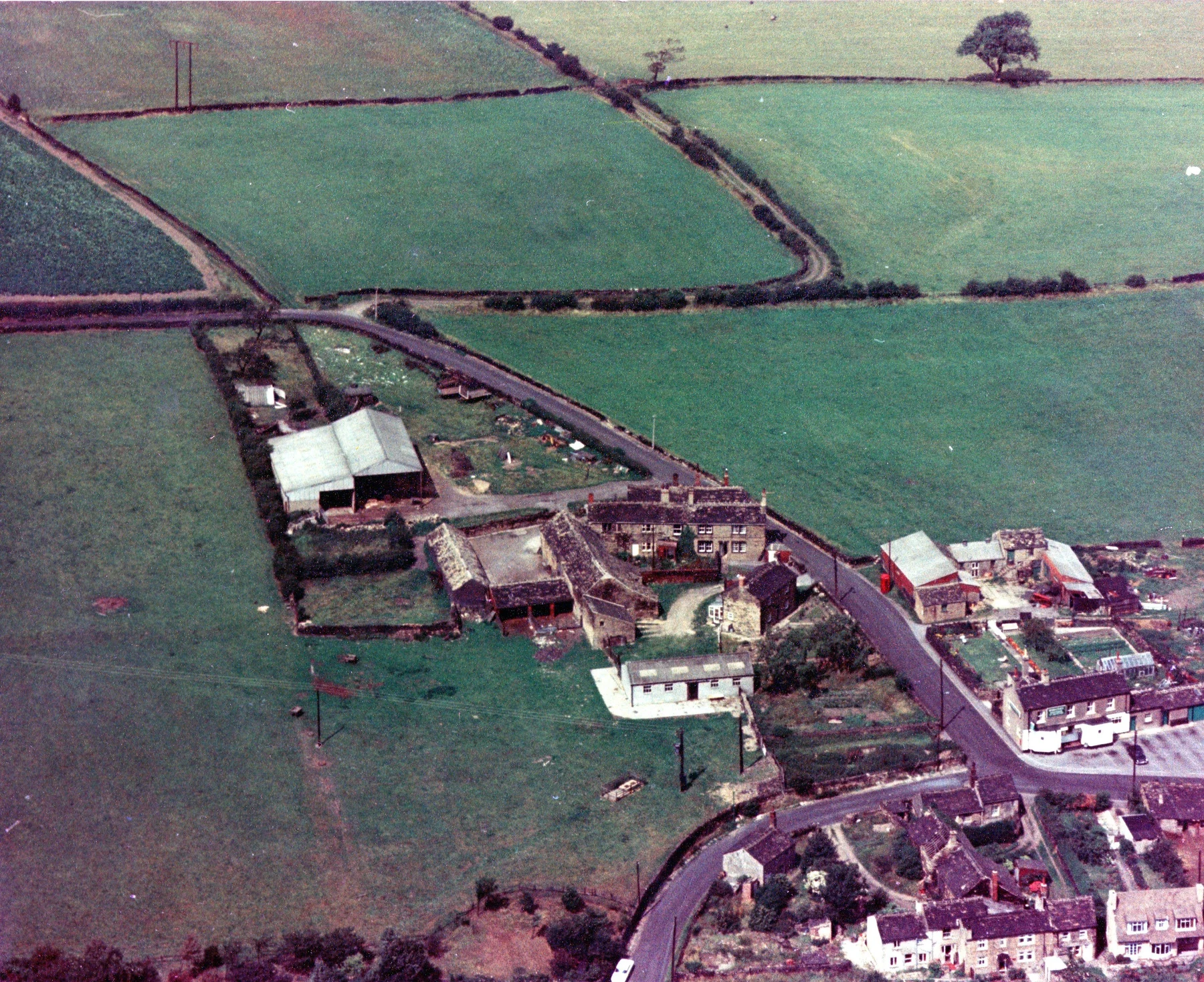 Historic aerial view of Briestfield, showing buildings beside winding roads and surrounding fields divided by boundaries.